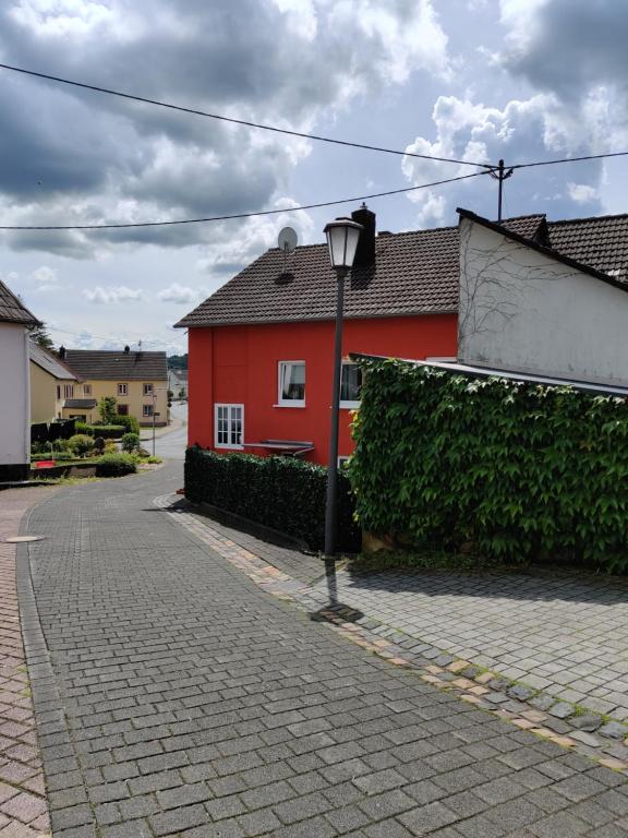 una casa roja con una luz de la calle en un camino de ladrillo en Ferienhaus am Sauerbrunnen, en Daun