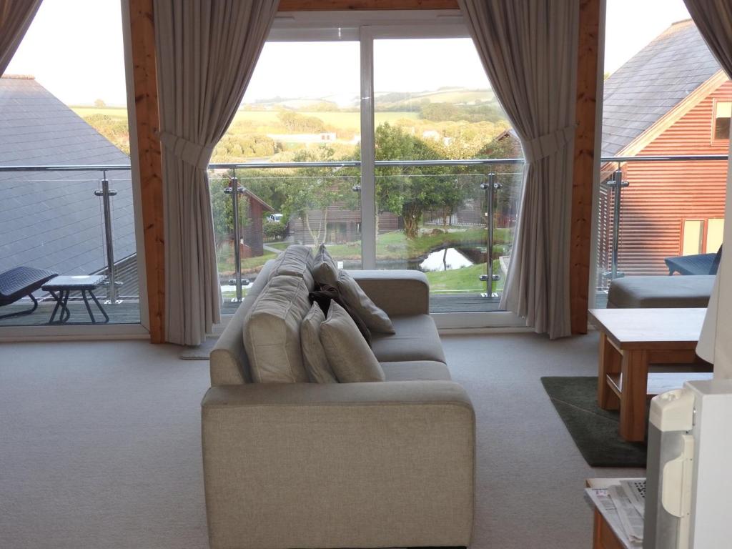 uma sala de estar com um sofá e uma grande janela em Peaceful relaxing home with leisure em Saint Columb Major