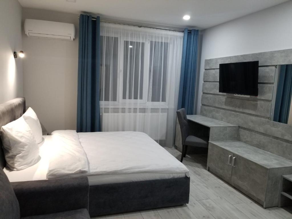 Schlafzimmer mit einem Bett, einem Schreibtisch und einem TV in der Unterkunft Новая и уютная квартира в центре in Uschhorod