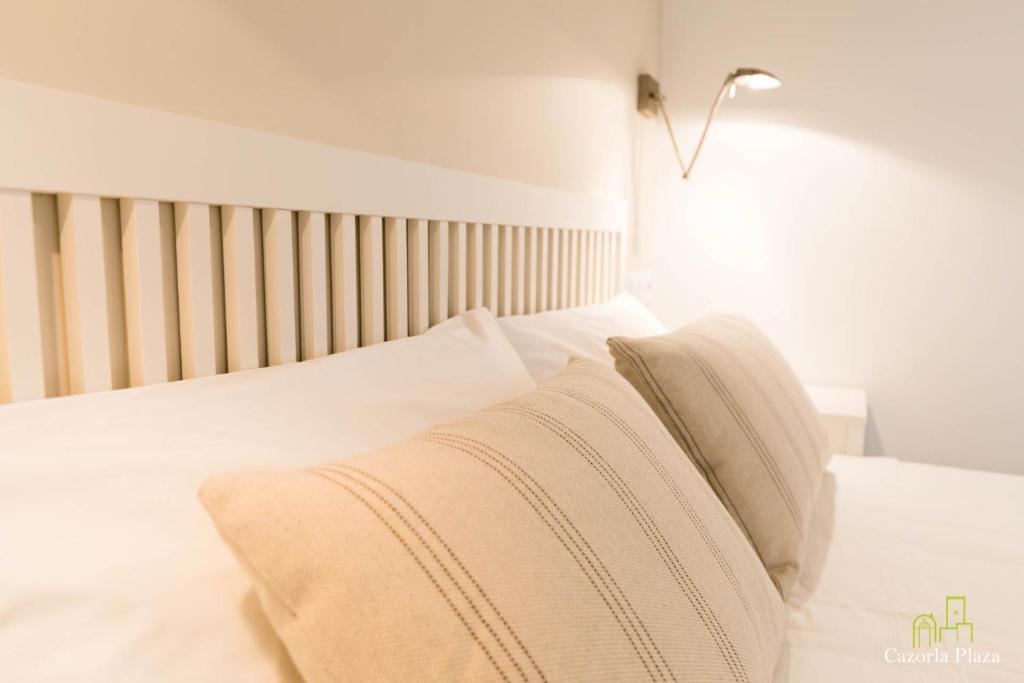 a bedroom with a bed with white sheets and pillows at Cazorla Plaza in Cazorla