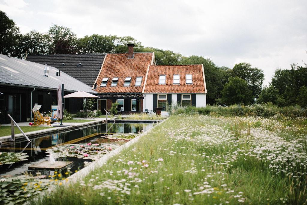 ein Haus mit einem Teich davor in der Unterkunft De Woeste Wieven op Erve Bonkert in Diepenheim