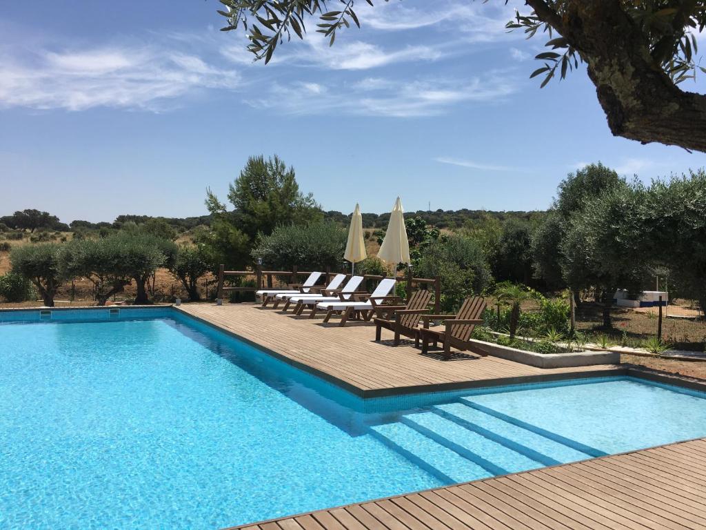 a swimming pool with chairs and umbrellas at Aleixo's House | Alentejo in Monforte