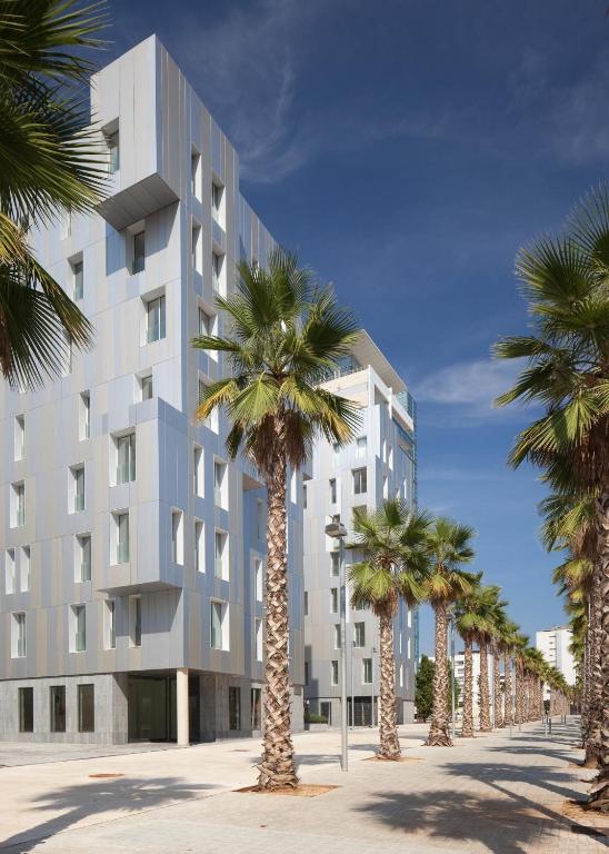 Hotel Lugaris Beach Apartments, a building with palm trees in front of it at Lugaris Beach Apartments in Barcelona