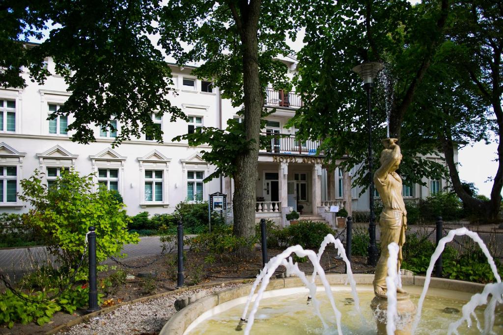 a statue in front of a fountain in front of a building at Hotel Apollo in Darłówko