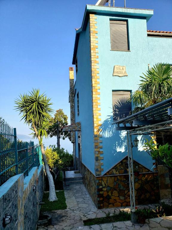a house with palm trees in front of it at Villa Angela in Vlorë
