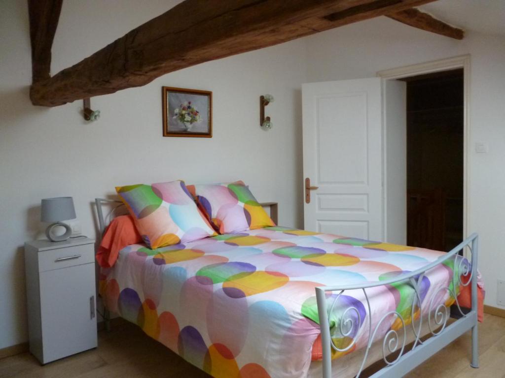 Un dormitorio con una cama con un edredón colorido. en HOME VACANCES 4 étoiles par CDT DORDOGNE, en Le Pizou