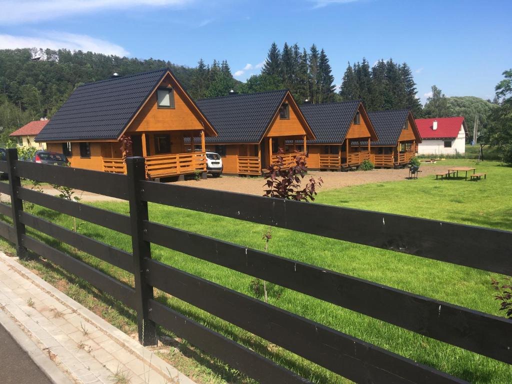 a row of log homes behind a fence at Domek letniskowy in Wünschelburg