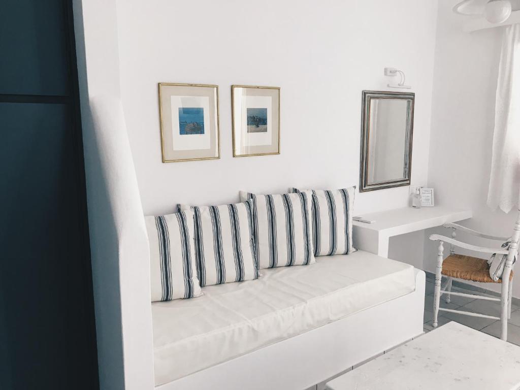 a white living room with a couch with striped pillows at Nautilos in Tinos
