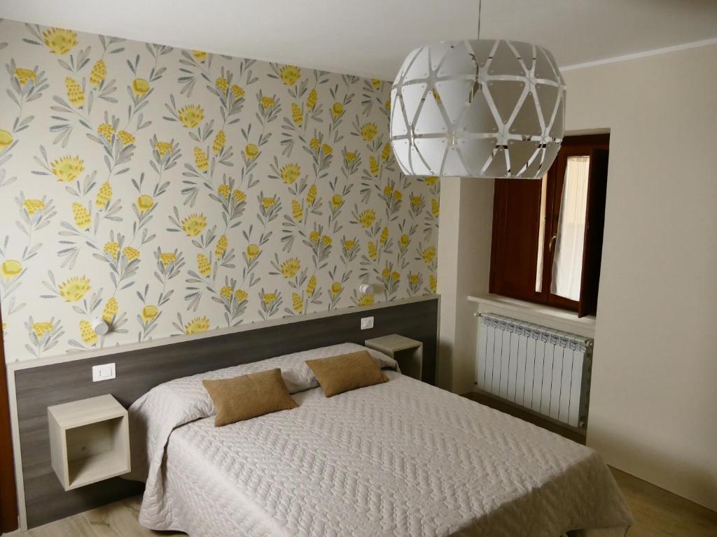 1 dormitorio con cama y pared de flores en IL NIDO L'Aquila en LʼAquila