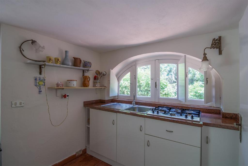 eine Küche mit einem Waschbecken und einem Fenster in der Unterkunft Case di Berto in Capo Vaticano