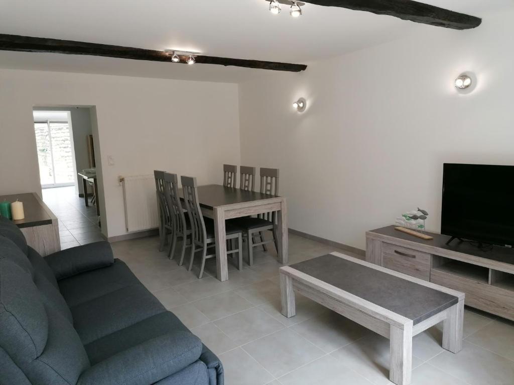 ein Wohnzimmer mit einem Sofa, einem Tisch und einem TV in der Unterkunft "Chez la Joe" in Thélonne