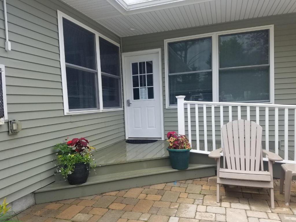 a porch with a white door and a chair and flowers at The Lakehouse Inn Geneva in Geneva-on-the-Lake