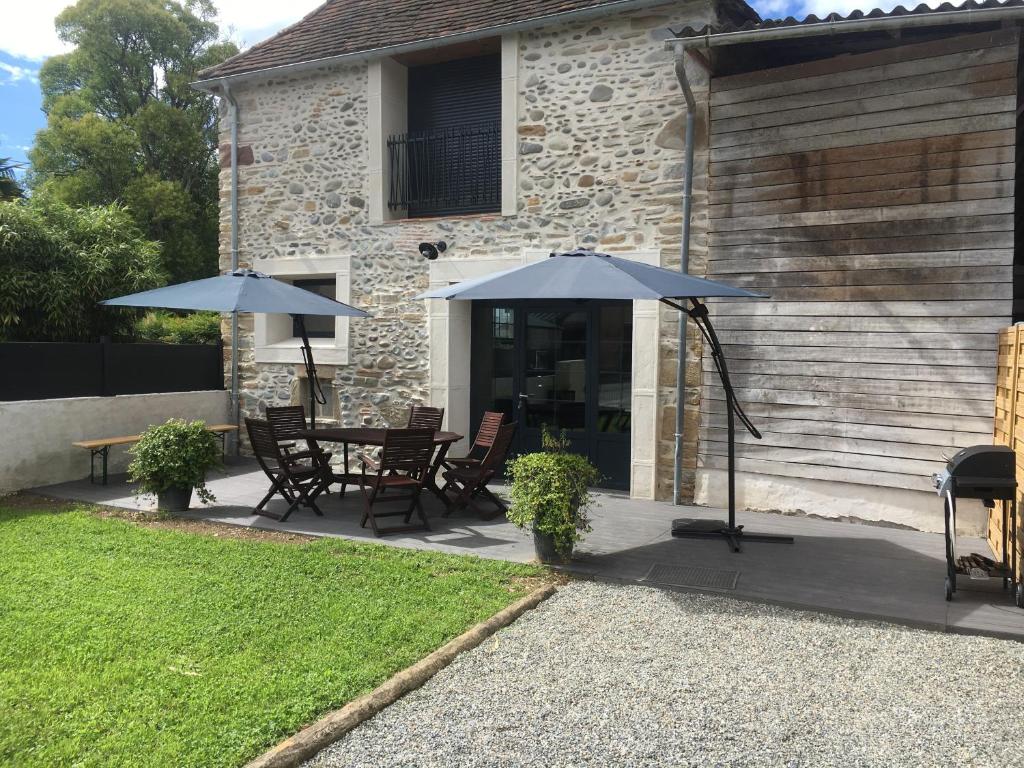 - une terrasse avec 2 parasols, une table et des chaises dans l'établissement Gîte Petitou, à Jasses