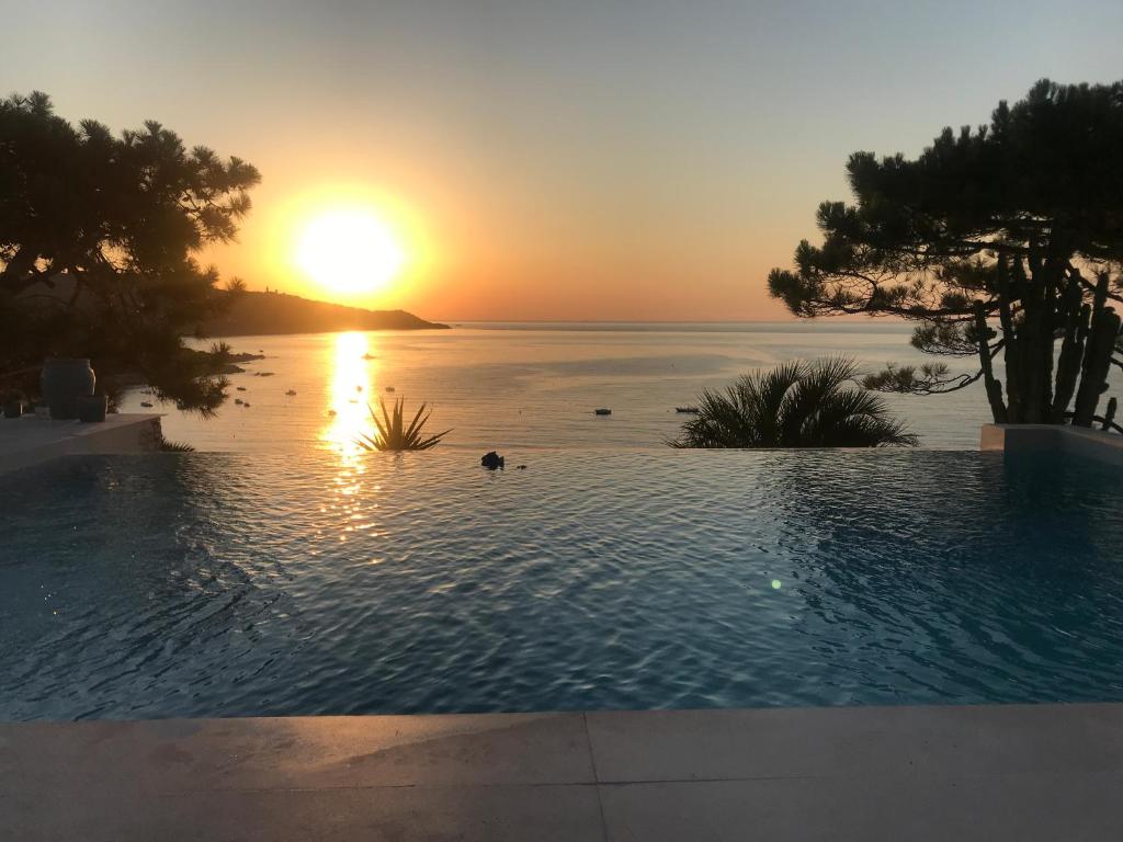 a swimming pool with the sunset in the background at Villa Mael in Ramatuelle