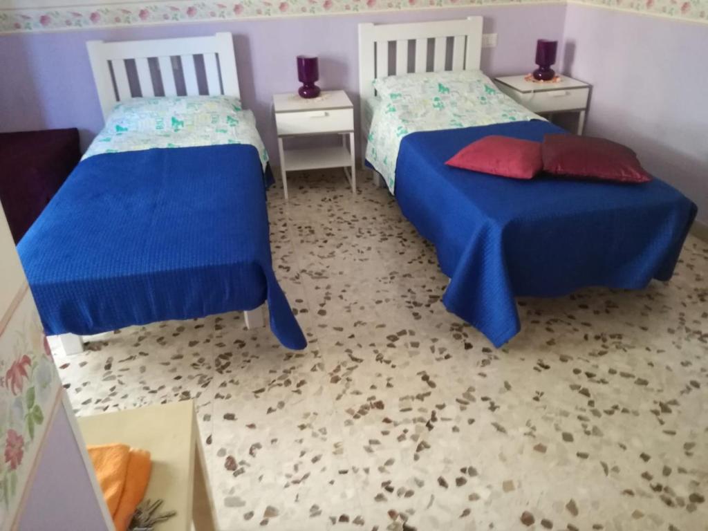 1 dormitorio con 2 camas con sábanas azules y almohadas rojas en CASA NINO, en Roma