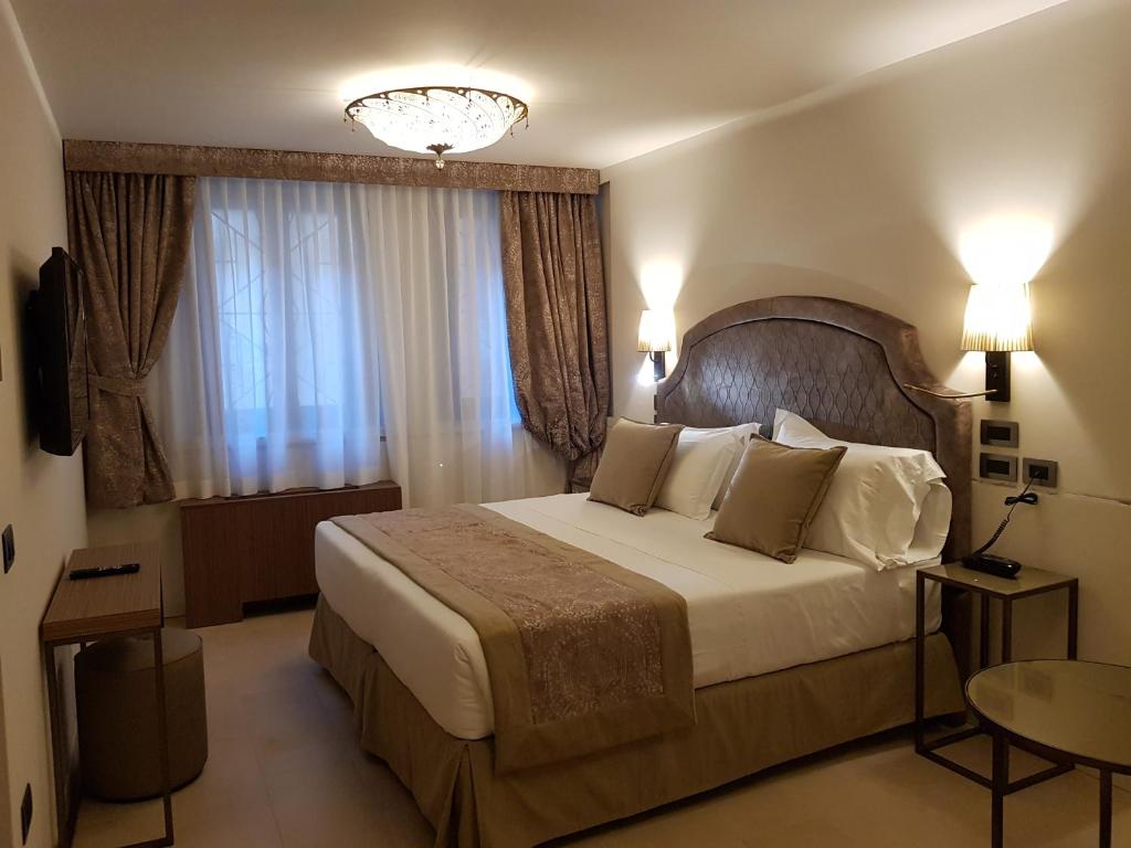a hotel room with a large bed and a chandelier at Hotel Aquarius Venice - Ascend Collection in Venice