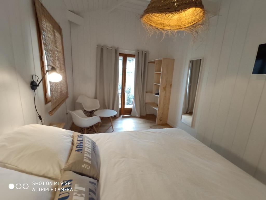 een slaapkamer met een wit bed en een raam bij Centre Cap-ferret, les chambres du phare, océan in Bélisaire