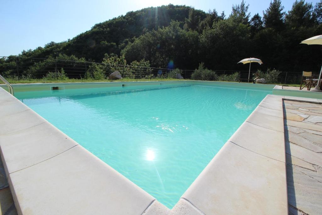 a large blue swimming pool with a mountain in the background at laCelletta Country House in Urbino