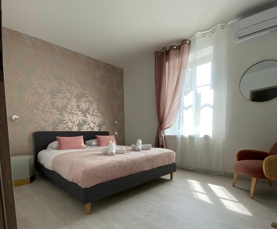 a bedroom with a bed with pink pillows and a window at Le Nid du Faubourg in Beaune