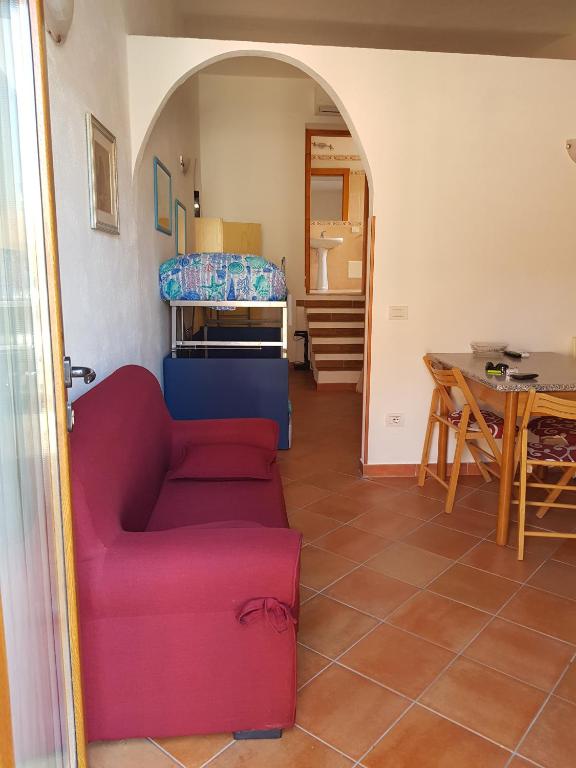 a living room with a red couch and a table at stupenda casetta in centro storico in La Maddalena