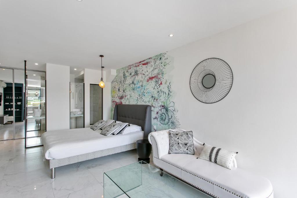 Cette chambre comprend deux lits, un canapé et un miroir. dans l'établissement Village Naturiste - Le Diamond X Héliopolis Luxe, au Cap d'Agde