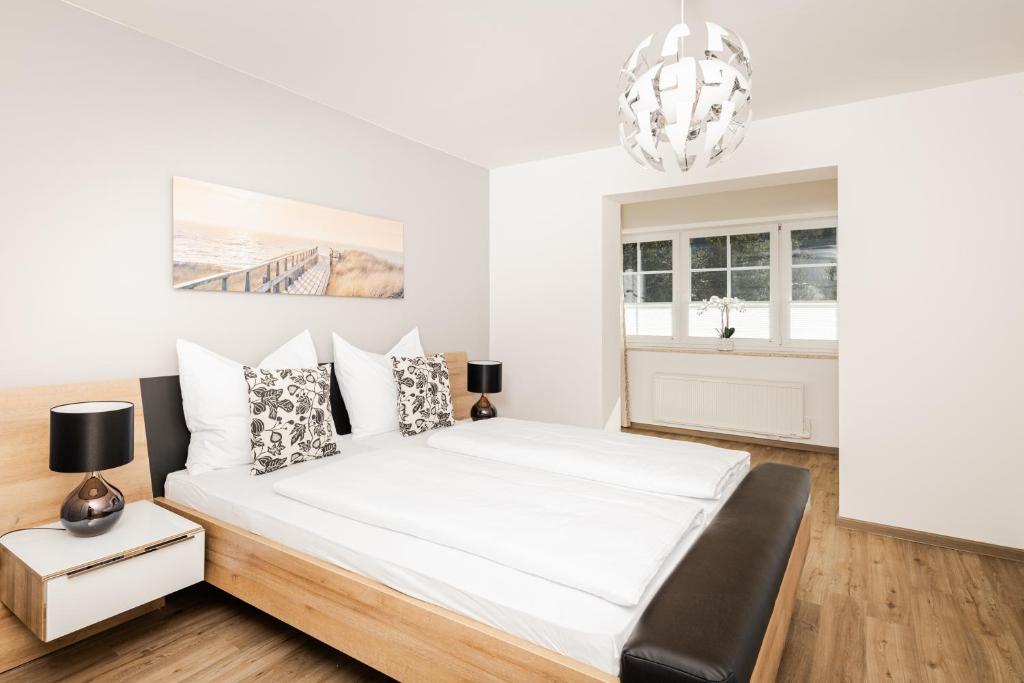 a white bedroom with a bed and a chandelier at Leonhardsblick Appartements in Tamsweg