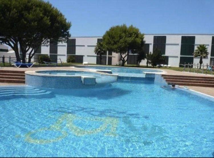 a large blue swimming pool in front of a building at Stupendo Appartamento a Cala’n Bosch Minorca in Cala en Bosc