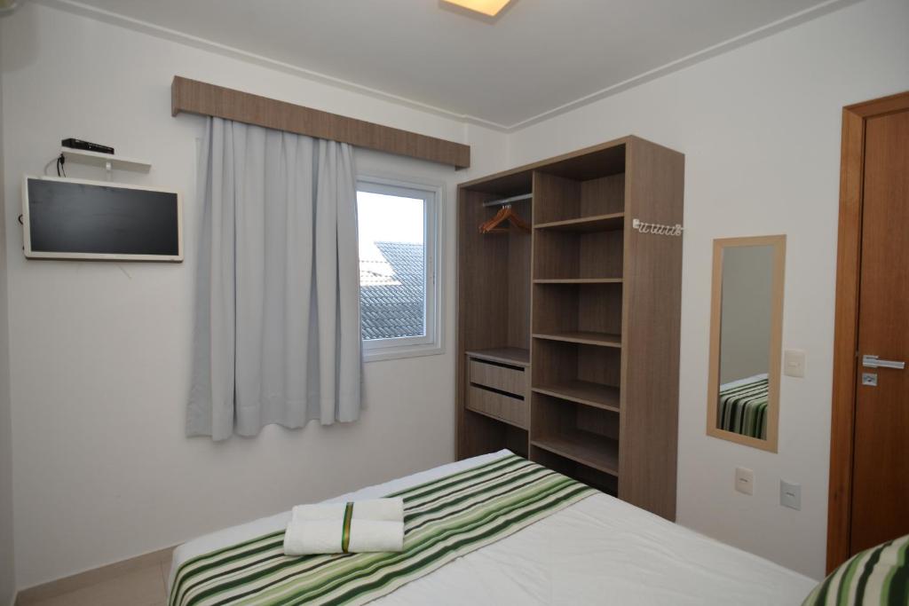 een slaapkamer met een bed en een tv aan de muur bij Pousada Villa Maciel in Bombinhas