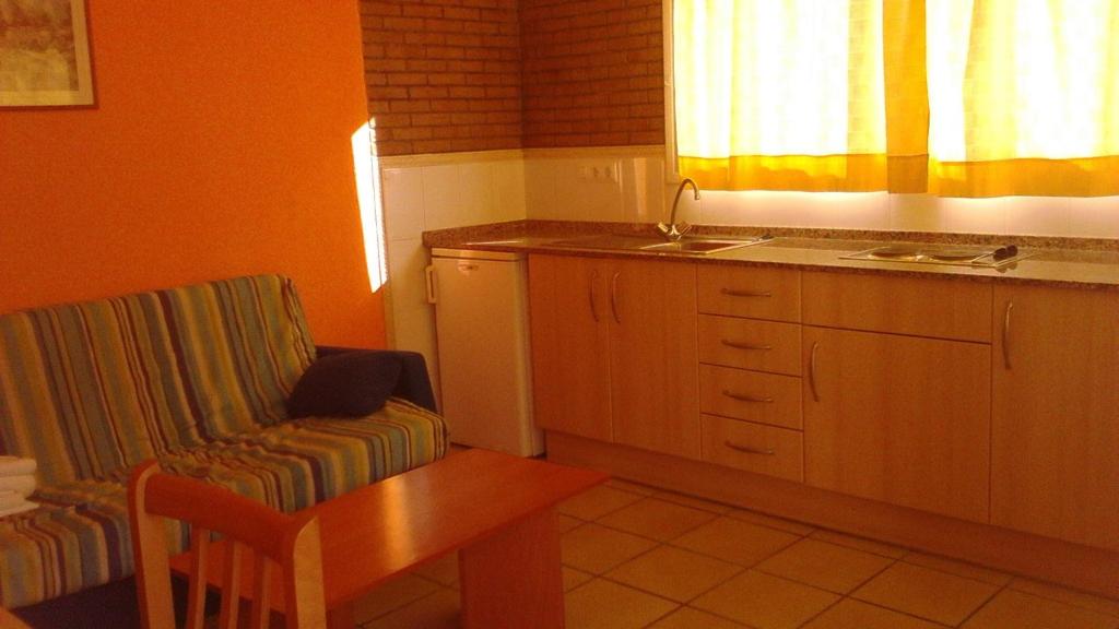 a kitchen with a table and a chair and a sink at Apartamentos Famara in Lloret de Mar