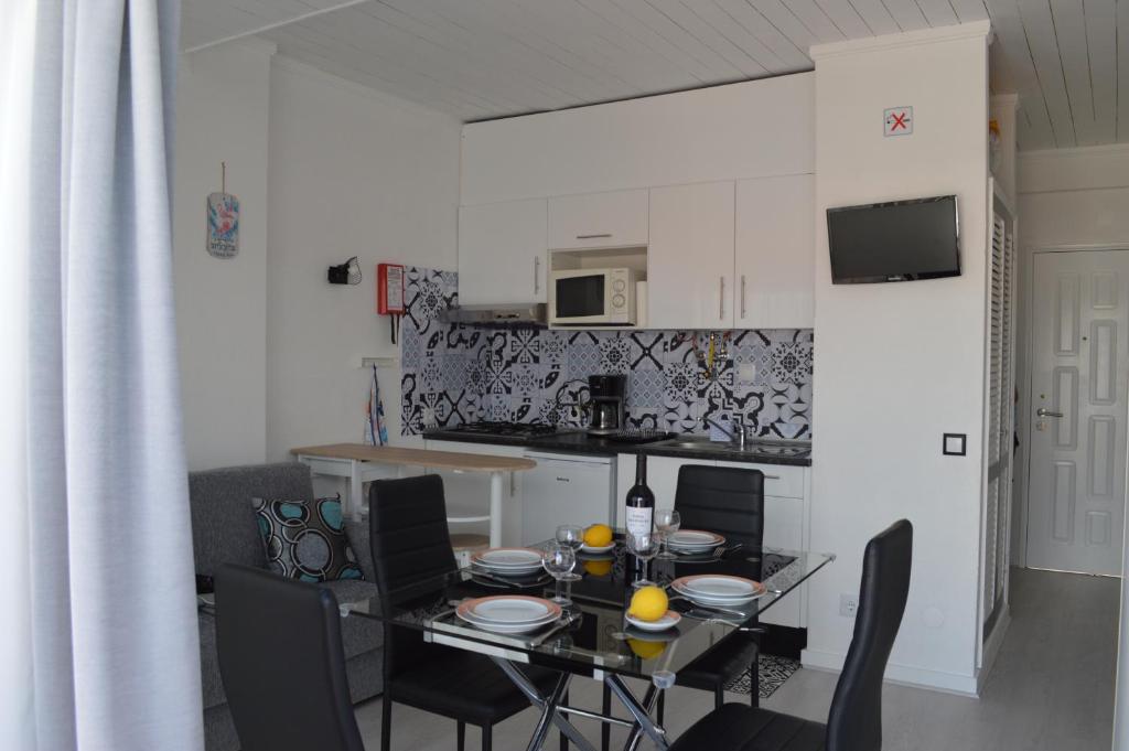 a dining room with a table and chairs and a kitchen at Joli studio rénové Emplacement idéal front de mer in Cabanas de Tavira