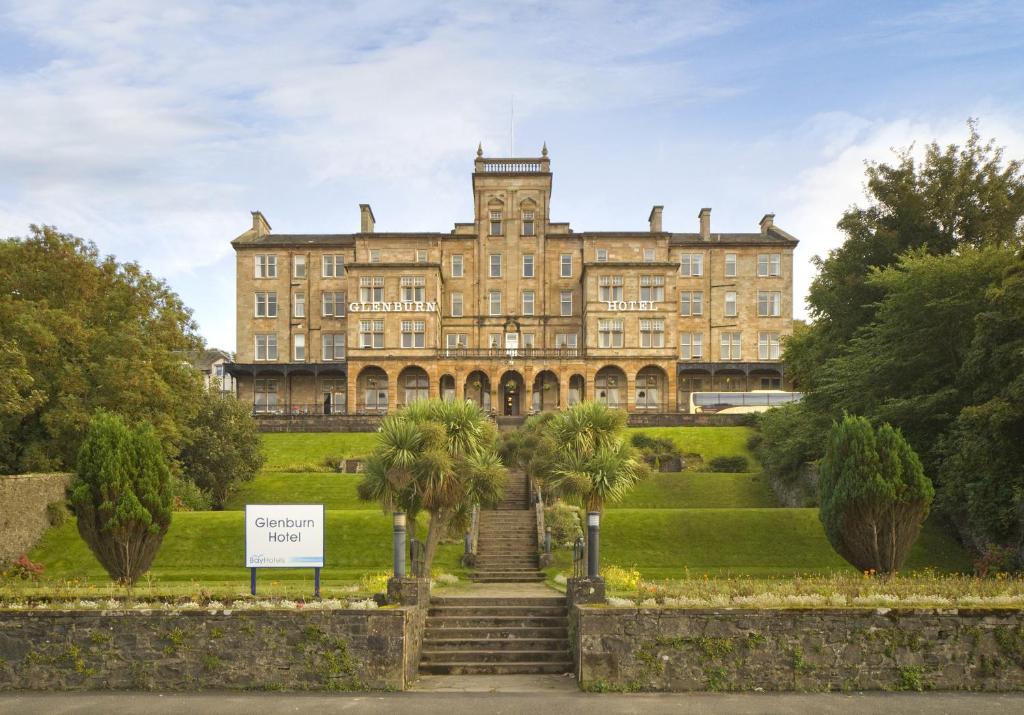 un grand bâtiment avec des palmiers devant lui dans l'établissement The Glenburn Hotel, à Rothesay