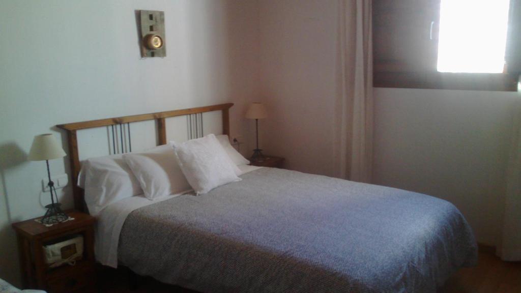 una camera da letto con un letto con cuscini bianchi e una finestra di Apartamento rural en Gátova a Gátova