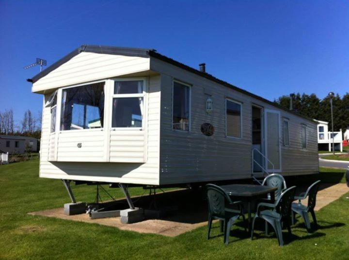 a tiny house on a trailer with a table and chairs at Haven Devon Cliffs Caravan in Budleigh Salterton