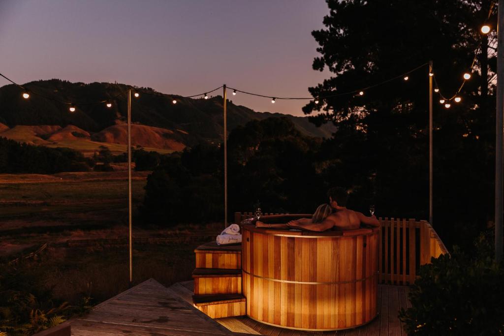 a man sitting in a hot tub at night at Cottage 103 in Waikanae