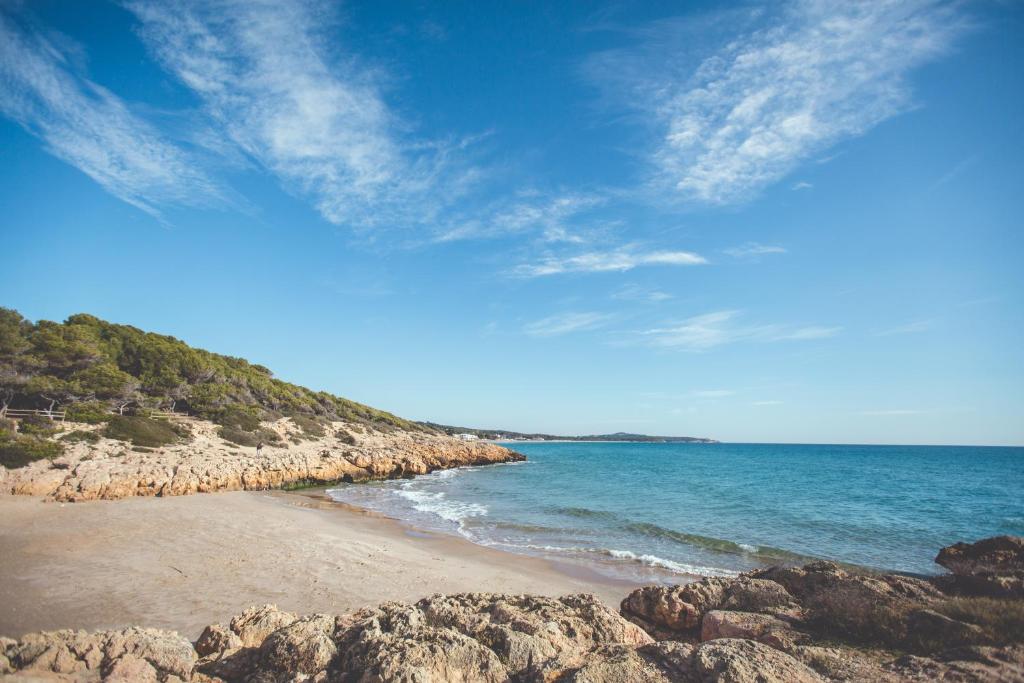 una playa con rocas y el océano en un día soleado en Apt Costa Dorada 2 by MarCalma, en Creixell