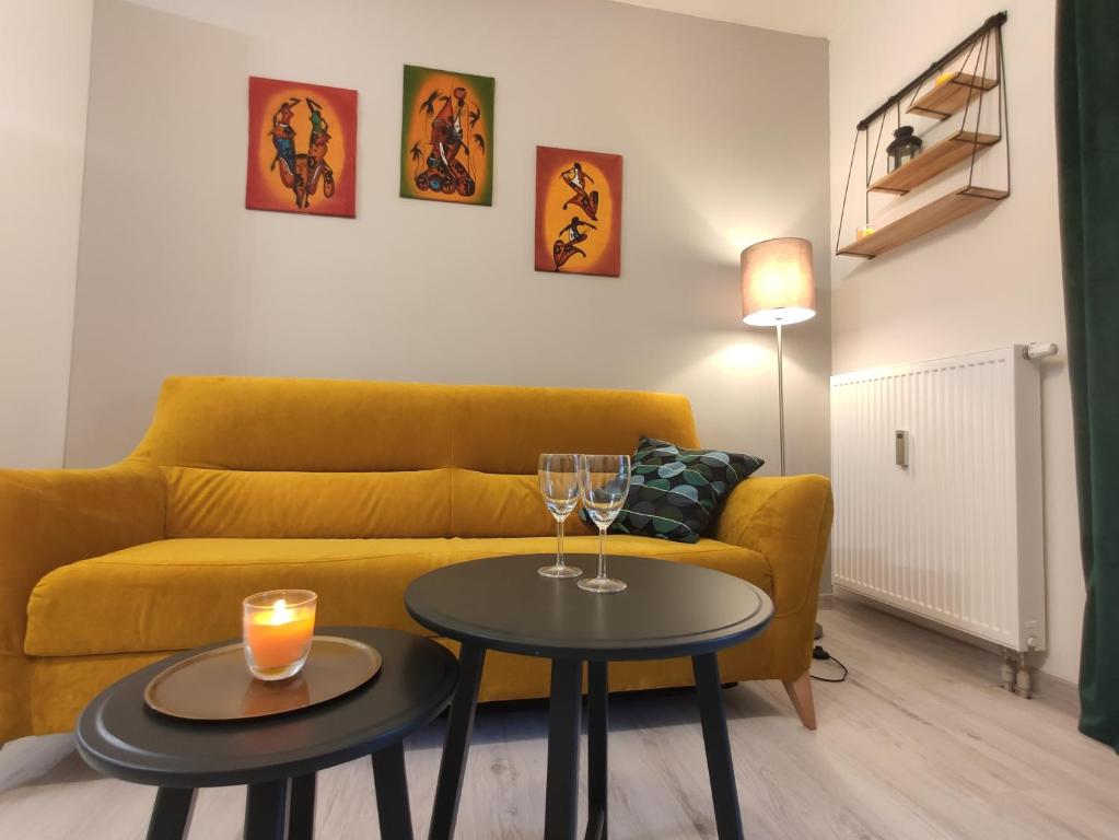 a living room with a yellow couch and two tables with wine glasses at Apartament Olsztyn Twoja Przestrzeń in Olsztyn