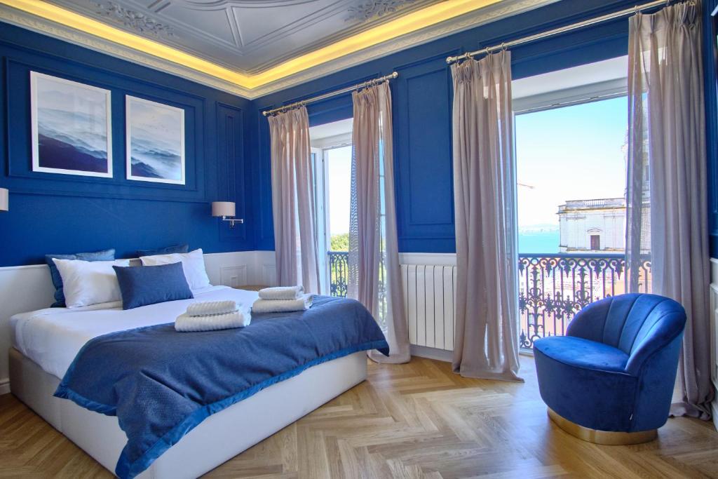 een blauwe slaapkamer met een bed en een blauwe stoel bij Luxurious Alfama Riverview in Lissabon