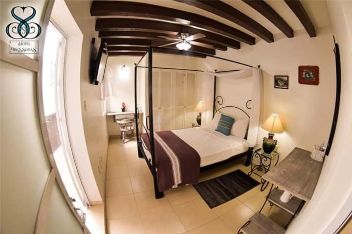 a bedroom with a bed and a table and a window at Hotel Tres Sofias in Querétaro