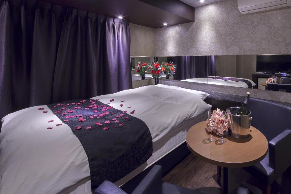 una habitación con una cama y una mesa con flores. en ホテルオリジン Hotel Origin 男塾ホテルグループ, en Hiroshima