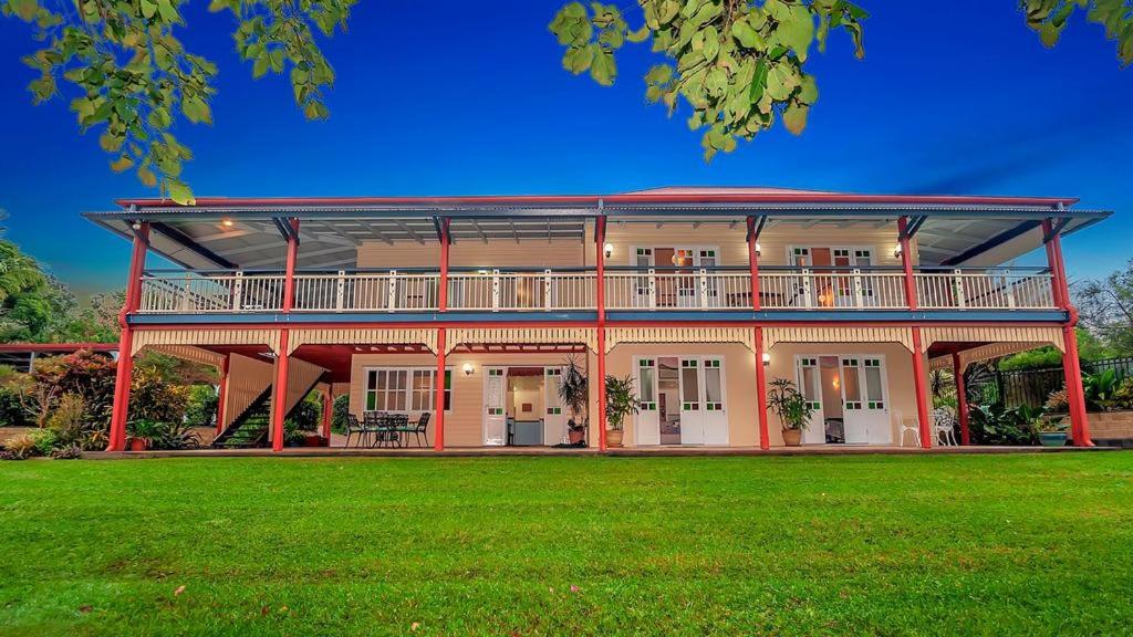 een groot huis met een grote tuin met groen gras bij Williams Lodge in Yungaburra