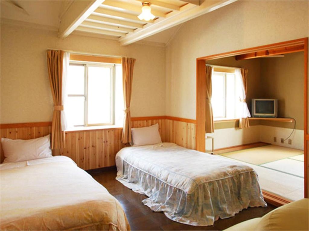 een slaapkamer met 2 bedden, een spiegel en 2 ramen bij olive no sato vingh four eyes shodoshima / Vacation STAY 79065 in Kusakabe
