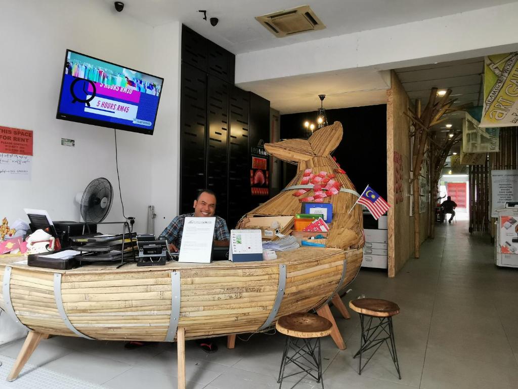 a man sitting at a counter with a wooden boat at Leo Backpackers @ Central Market in Kuala Lumpur