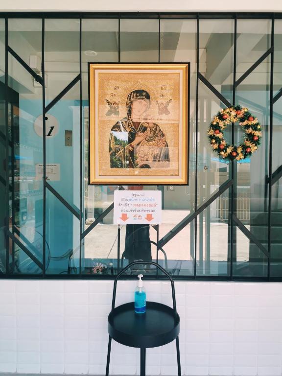 A small seating point by a glass entrance, decorated with framed art and a wreath.