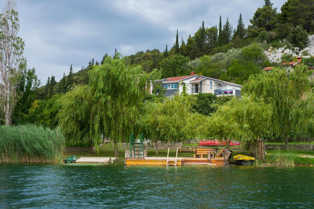 a house on the shore of a lake with a boat at Apartmani Galić in Ploče