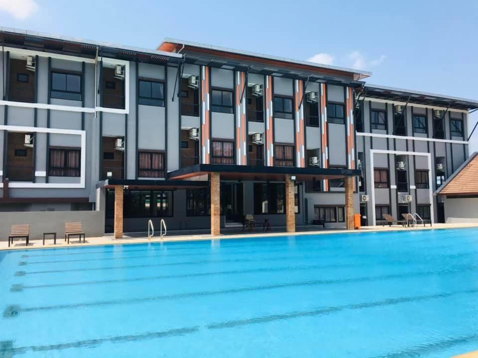 a large building with a swimming pool in front of it at Buathong Pool Villa in Ban Khung Taphao