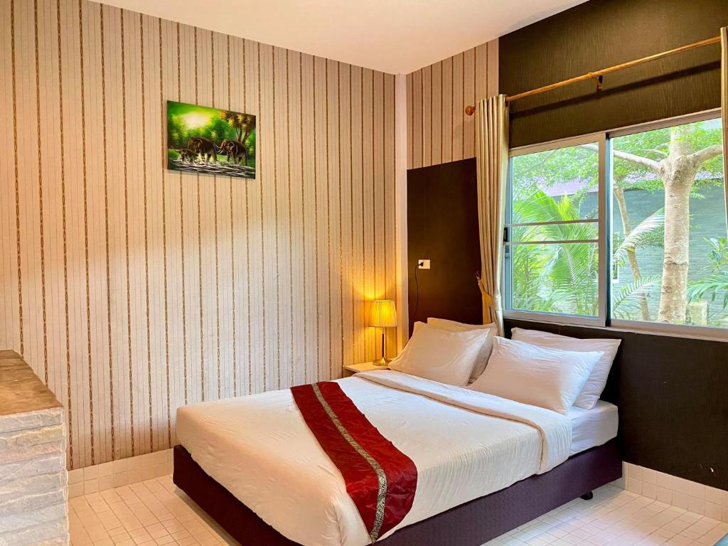 a bedroom with a large bed with a window at Canal Resort in Nai Yang Beach