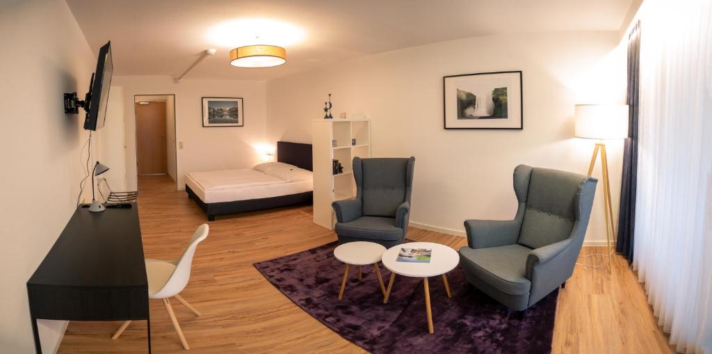 a living room with two chairs and a table and a bed at Hotel Quellenhof Bad Urach in Bad Urach