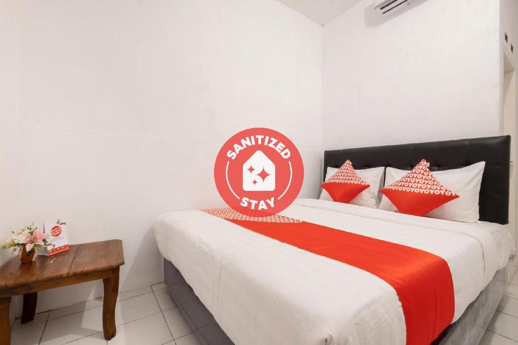 una camera da letto con un letto con cuscini rossi e bianchi di OYO 2394 Hotel Brosta a Yogyakarta
