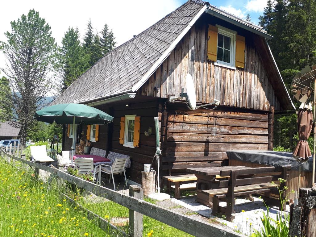 eine Blockhütte mit einem Picknicktisch und einem Sonnenschirm in der Unterkunft Almhütte in Ferlach