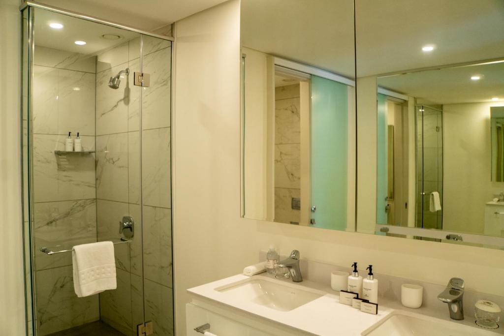 a bathroom with a sink and a shower with a mirror at The Leonardo in Johannesburg